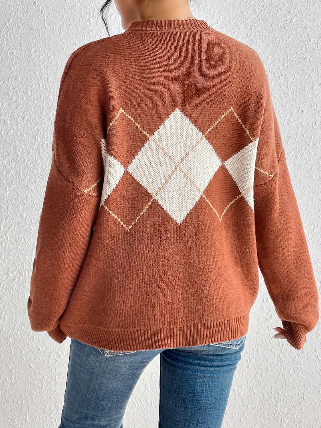 Showcasing the back of the orange color dropped shoulder sweater.